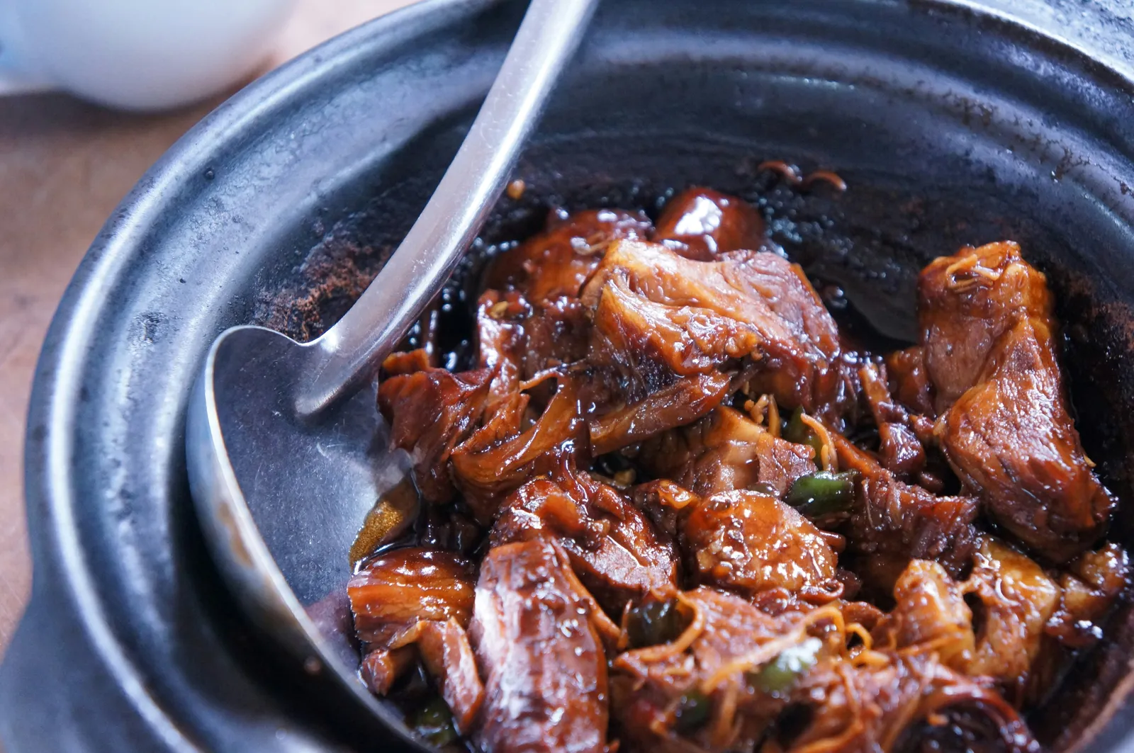A heavy dark pot of braised beef stew with caramelized chunks of chuck roast, onions, and glossy sauce