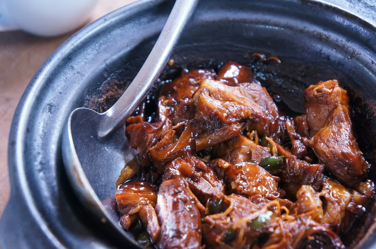 A heavy dark pot of braised beef stew with caramelized chunks of chuck roast, onions, and glossy sauce