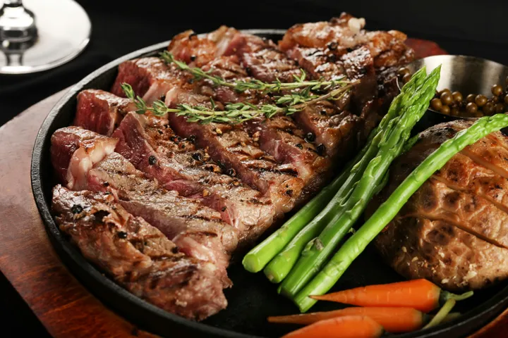 A medium-rare ribeye steak resting in a cast iron skillet after a high-heat sear