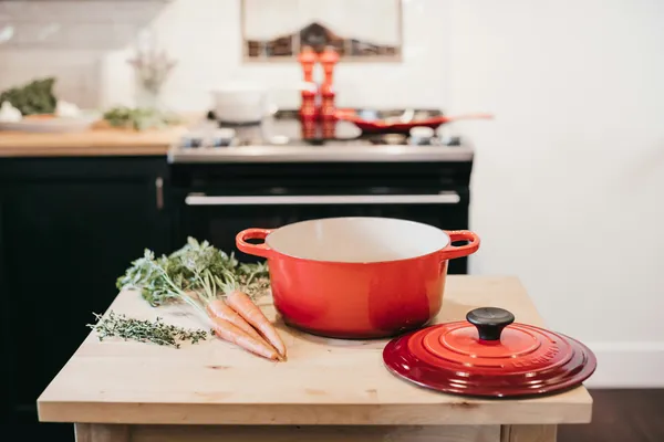 A red enameled cast iron dutch oven with the lid off, showing the cream enamel interior