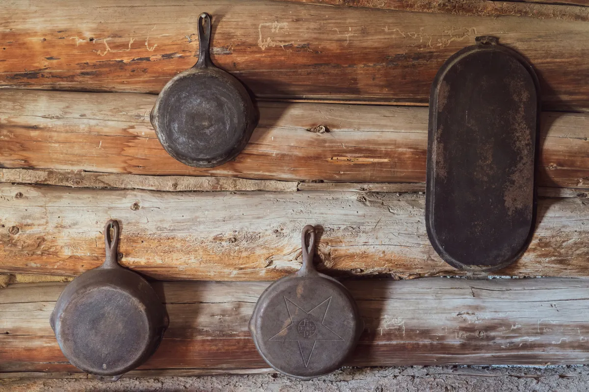 Cast iron skillets of different sizes hanging on a wooden wall, showing the range of skillet sizes