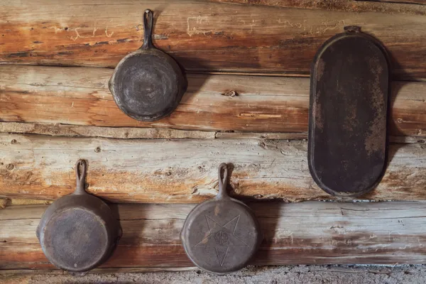 Cast iron skillets of different sizes hanging on a wooden wall, showing the range of skillet sizes