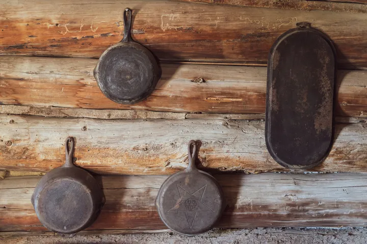 Cast iron skillets of different sizes hanging on a wooden wall, showing the range of skillet sizes