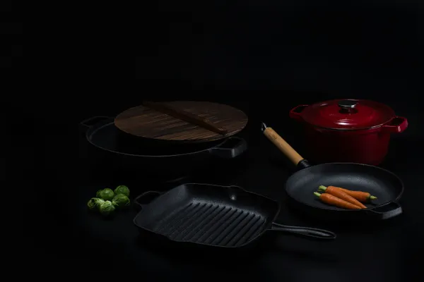 Bare cast iron skillet and grill pan on a dark surface with their cooking surfaces visible