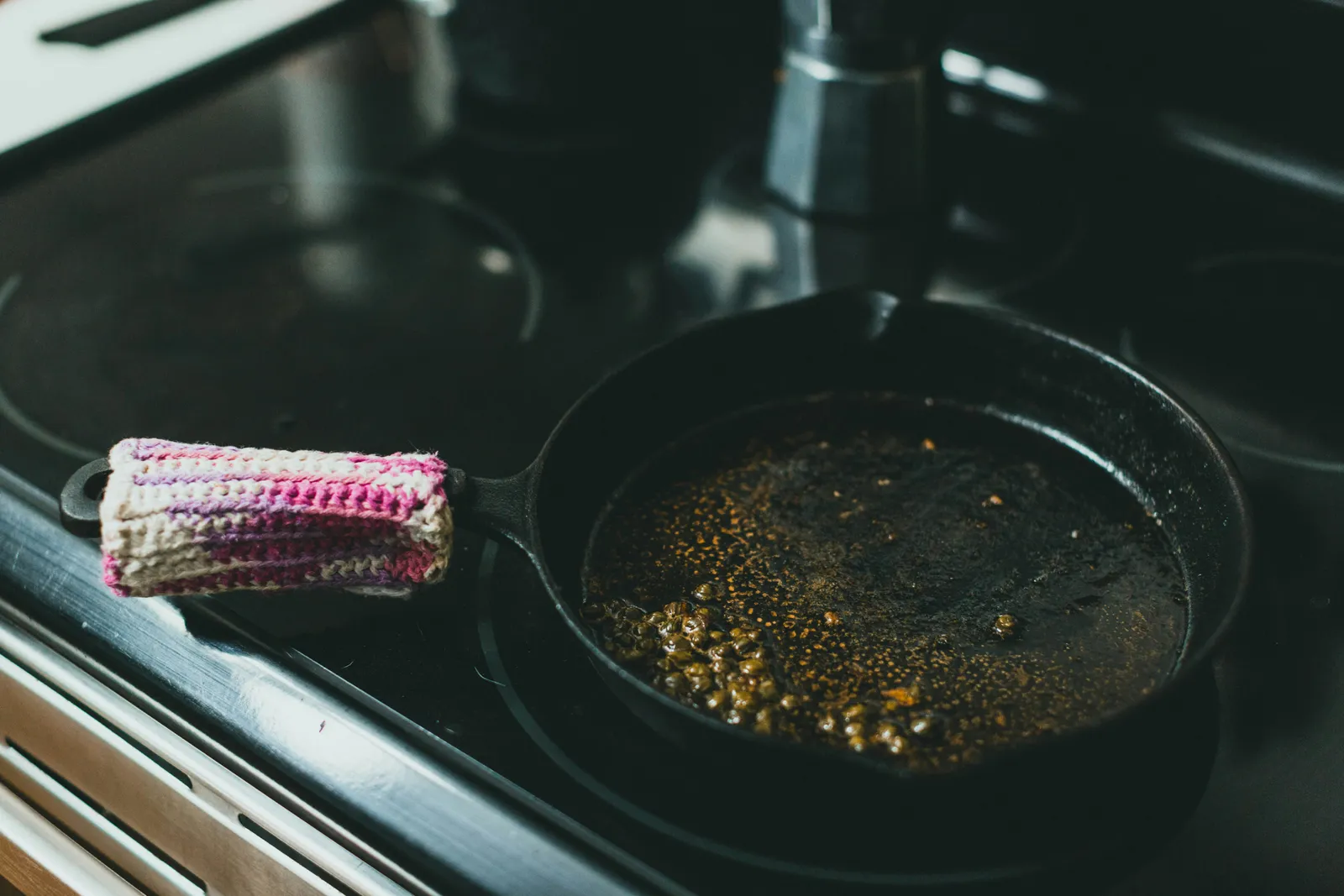 A cast iron skillet on a stovetop with residue from a previous cook, the kind of pan that needs re-seasoning