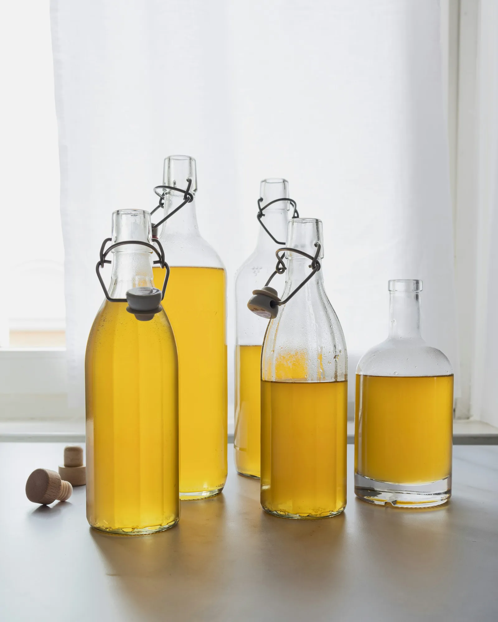 A lineup of glass bottles holding pale neutral cooking oils, the kind used for seasoning cast iron