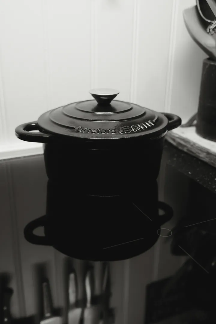A black enameled cast iron dutch oven with lid on an induction cooktop, the classic round shape