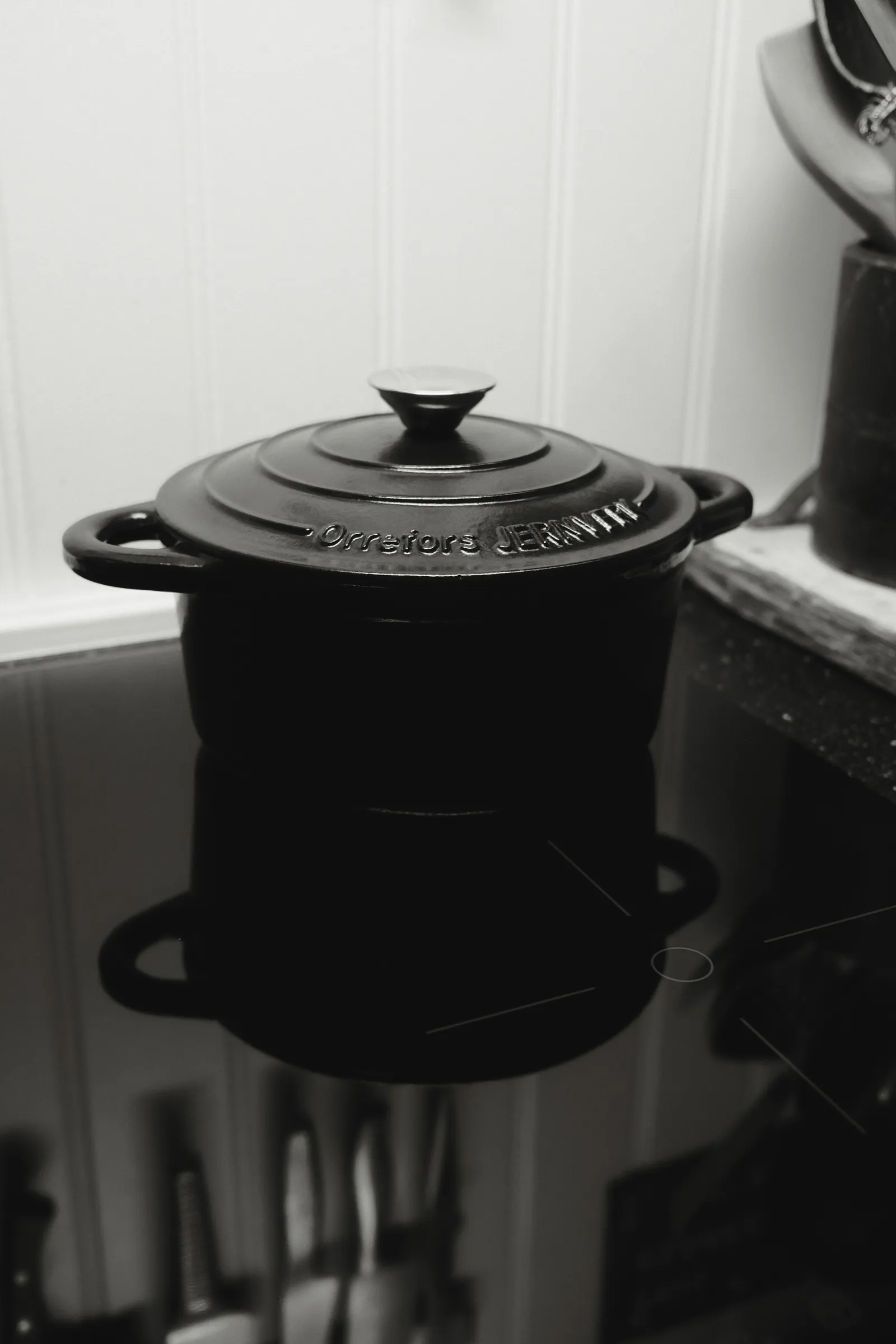 A black enameled cast iron dutch oven with lid on an induction cooktop, the classic round shape